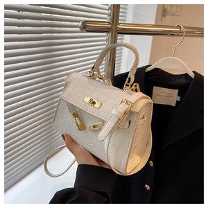 Close-up of white crocodile embossed leather bag with gold buckle and handle