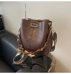 Detail of dark brown leather bucket bag with jacquard strap and woven handle on sofa