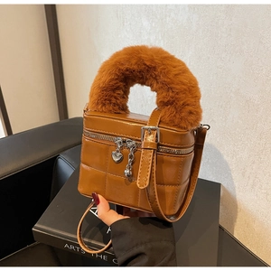 Detail einer braunen gesteppten Box-Tasche mit weichem Kunstfellgriff und Herz-Anhängern
