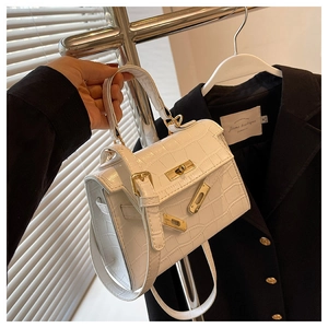 Detailed view of white crocodile pattern trapezoid bag with golden metal buckle and strap