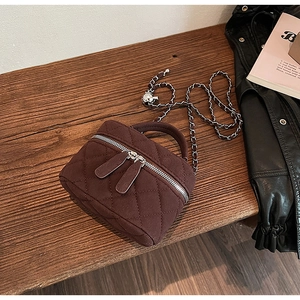 Detail of dark brown quilted crossbody bag with dual zippers and silver chain strap