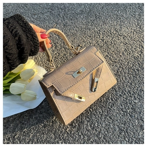 Detailed macro of beige croc-embossed texture and metallic turn-lock on the Kelly handbag