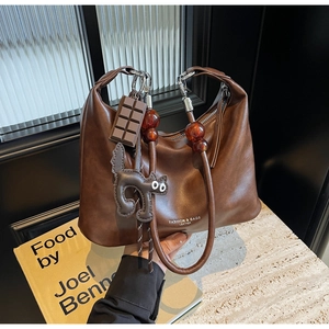 Close-up of dark brown leather handbag with chocolate charm and amber bead handle detail