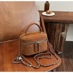 Detail of brown quilted suede bucket bag featuring silver chain and adjustable metal ball