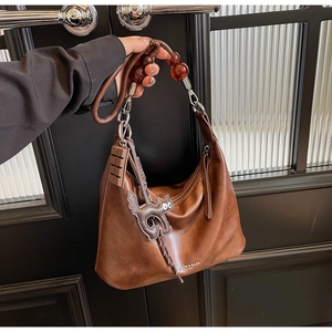 Detail of vintage brown leather handbag featuring amber bead handle and cute cat pendant charm