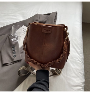 Detail of vintage brown leather bucket bag with woven handle and jacquard strap