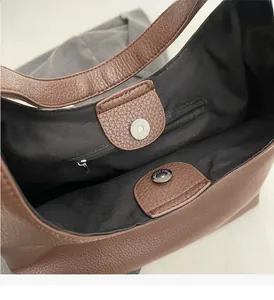 Macro detail of brown leather bag showing magnetic closure and internal zipper pocket