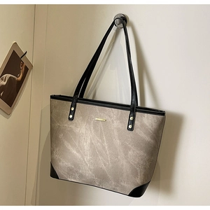 Detail of grey textured faux leather tote bag featuring gold rivets and black shoulder strap