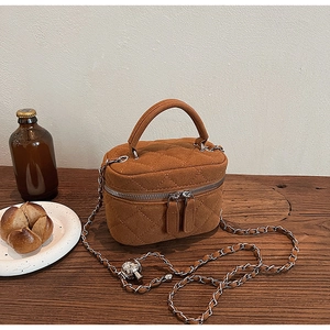 Detail shot of brown quilted chain bag with suede texture and top handle design
