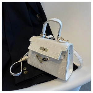 Detail of white crocodile texture handbag with gold metal lock and leather top handle