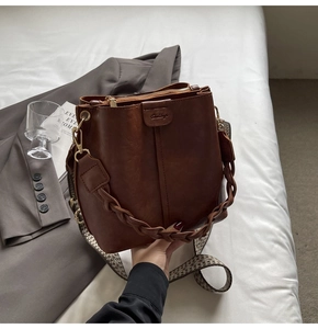 Detail of vintage brown bucket bag with woven handle and jacquard embroidered strap