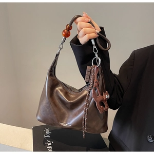 Detail of dark brown leather hobo bag with a cute cat pendant and amber bead charms