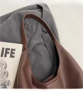 Detailed close-up of brown litchi pattern PU leather shoulder bag on a grey suit blazer