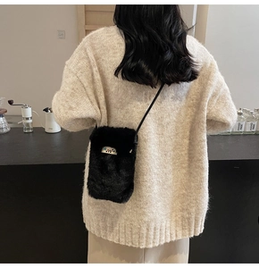 Détail d'un petit sac à bandoulière en peluche noire avec texture douce en fausse fourrure
