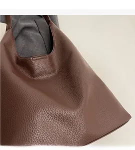 Close-up of caramel brown lychee grain PU leather shoulder bag on a grey blazer