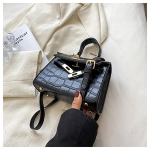 Detail of black crocodile texture leather bag with elegant golden twist-lock buckle
