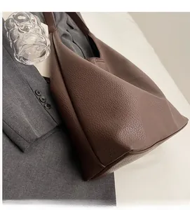 Close-up of dark brown lychee-patterned PU leather texture on a flexible Hobo shoulder bag