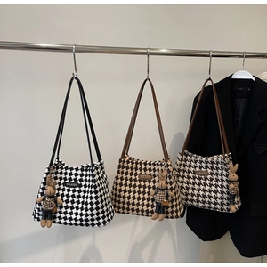 Three knit tote bags in checkers and houndstooth patterns with rabbit charms on hangers