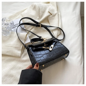 Detail of black crocodile pattern leather handbag with elegant gold metal turn-lock closure