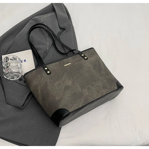 Macro detail of dark grey tote bag with gold logo and reinforced leather corners