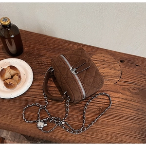 Top macro view of brown quilted bucket bag with golden chain and metal adjustment ball
