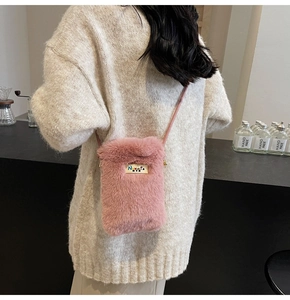 Détail du sac bandoulière rose en fausse fourrure avec plaque logo dorée et sangle