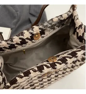 Detail view of houndstooth tote bag featuring gold magnetic buckles and tweed texture