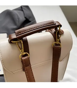 Detailed close-up of premium cream leather bag with dark brown handle and gold hardware