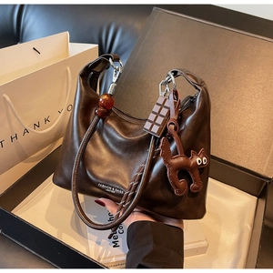 Detail of dark brown leather handbag with cat charm and amber bead handle on box