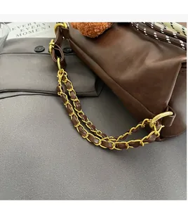 Detail of brown leather bag with golden chain strap and metallic hardware accents