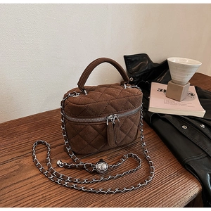 Detail view of brown quilted suede bucket bag with silver chain on wooden table