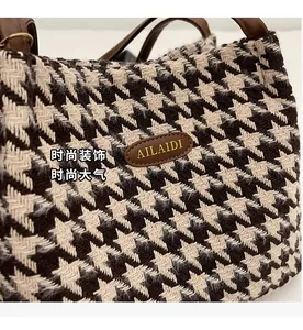 Close-up of houndstooth fabric texture and brown leather logo patch on tote bag