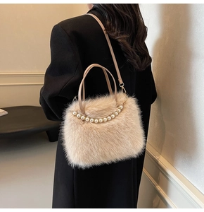 Détail d'un sac à main beige en fausse fourrure avec poignée en perles sur un blazer