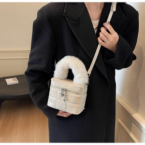 Detail der beigen gesteppten Box-Tasche mit weißem Kunstfellgriff und Herz-Reißverschluss