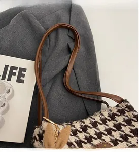Detail of houndstooth tote bag featuring brown leather handles and a cute bunny ear charm
