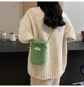 Gros plan du sac bandoulière vert en fausse fourrure pelucheuse avec plaque métallique