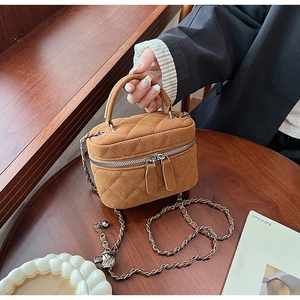 Detail of brown quilted suede box bag with gold-tone chain strap and double zipper