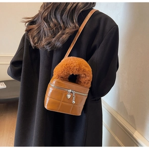 Detail der gesteppten Kasten-Tasche in Karamell mit Plüschgriff und Herz-Anhänger