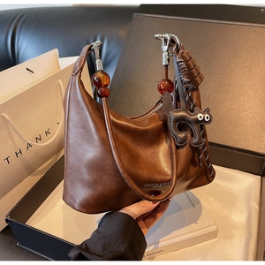 Detail of matte brown leather bag with bead strap and playful chocolate cat charms