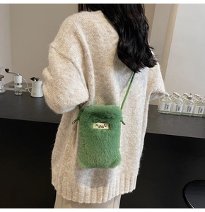 Détail d'un sac bandoulière en peluche verte avec cordon et plaque logo en métal