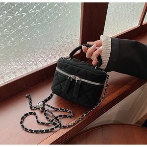Detail of black quilted leather mini bucket bag with silver chain strap and top handle
