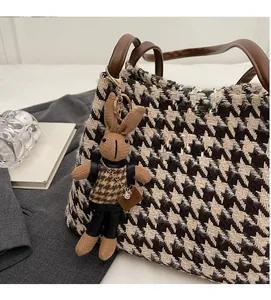 Detail shot of houndstooth fabric tote bag with a cute rabbit charm and leather branding