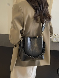 Retro black leather bucket bag with wide geometric woven strap shown on a model