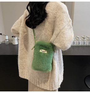 Détail d'un sac bandoulière en fausse fourrure vert vif avec logo sur pull en maille blanc