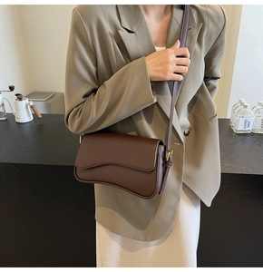 Close-up of dark brown litchi pattern leather bag with unique wavy curved flap