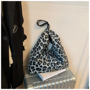 Detailaufnahme der Leoparden-Handtasche mit Metall-Logo auf strukturiertem Stoff