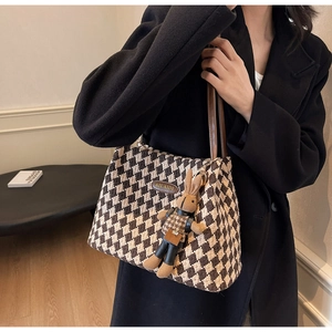 Detail of retro houndstooth tote bag featuring a leather handle and cute rabbit charm accessory