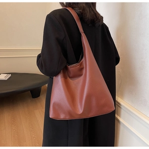 Detail of soft pebble grain dark brown PU leather tote bag shown on model's shoulder