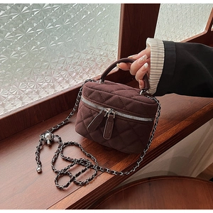 Detail of dark brown quilted crossbody bag with metal chain strap and twin zippers