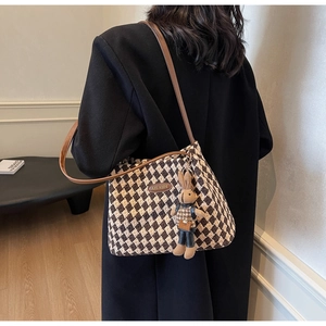 Detail of vintage brown plaid tote bag with cute rabbit pendant on a black coat